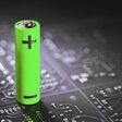 A lithium-ion battery stands on the background of electronic circuit boards.