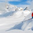 Skier skiing downhill in high mountains in fresh powder snow.