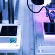automatic robot arm with vacuum sucker working in the production line and assembling smartphone screens in the new innovative and high technology smartphone factory.