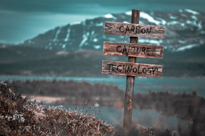 carbon capture technology text quote engraved on wooden signpost outdoors in landscape looking polluted and apocalyptic.