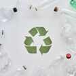 Flatlay composition with different empty plastic bottles and conceptual recycling sign made of paper in the center over white background. Sorting, recycling waste concept. Horizontal shot. Top view