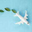 Sustainable Aviation Fuel. White airplane model, fresh green leaves on blue background. Clean and Green energy, Biofuel for aviation industry.