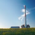 Waste incinerator in the evening sunlight, standing on a green meadow under blue sky.