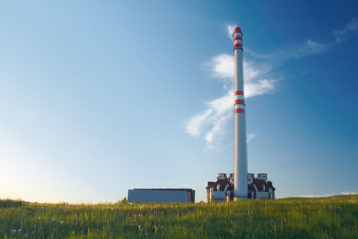 Waste incinerator in the evening sunlight, standing on a green meadow under blue sky.