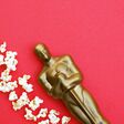 KHARKIV,UKRAINE - JULY 1, 2020: Plastic Oscar award on a red background with popcorn.