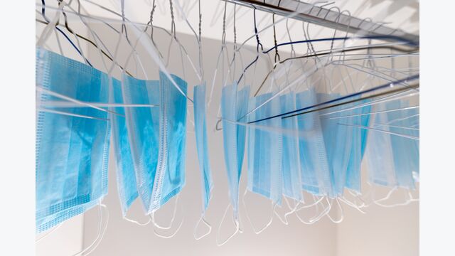 Disposable surgical masks hanging on hangers in a wardrobe closet. Concept of new normal. Concept of waring a mask becoming e new habit. Concept of adaptation during crisis and pandemic due to Covid.