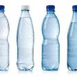 Collection of various cold bottles of water with drops isolated on white background