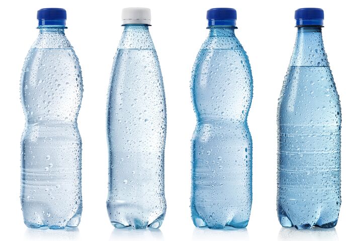 Collection of various cold bottles of water with drops isolated on white background