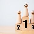 Wooden human standing on podium with ranking for winner business and sport competition concept.