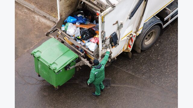 Garbage man operating garbage truck in residential area