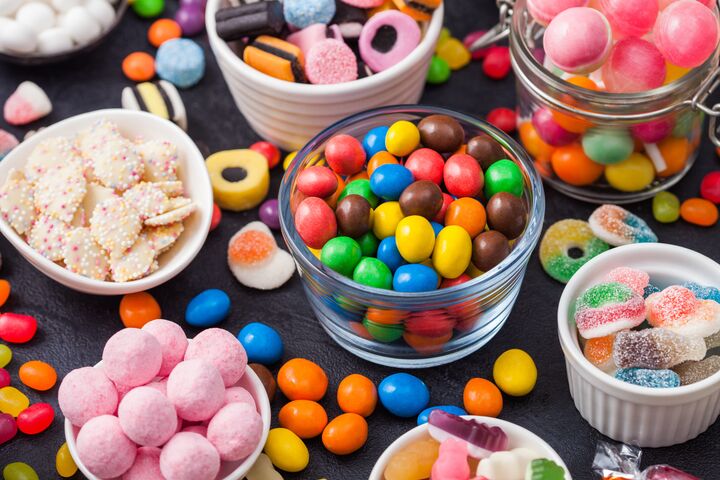 Variety of milk chocolate and jelly sugar gum sweets and candies on black. Best snacks for kids parties.