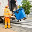 Worker of urban municipal recycling garbage collector truck loading waste and trash bin