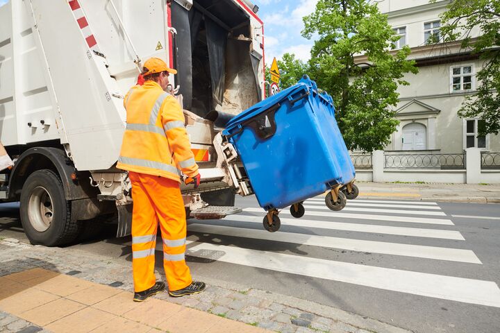 Worker of urban municipal recycling garbage collector truck loading waste and trash bin