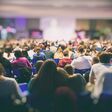 A lot of young people in a big hall listening to a speaker