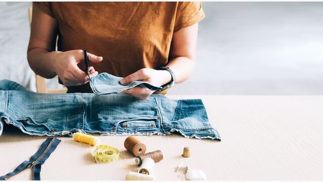 Woman repairs sews reuses fabric from old denim clothes. The concept of economical reuse of recyclable things. Homemade needlework hobby. Selective focus
