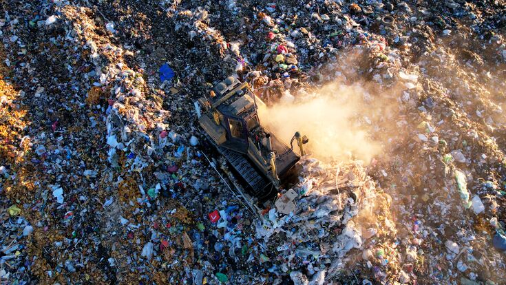© MaxSafaniuk - stock.adobe.com Landfill waste disposal. Garbage dump with waste plastic and polyethylene. Bulldozer at landfill working on rubbish disposal. Reduce greenhouse gas emissions and methane emissions.