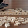 circularity word or concept represented by wooden letter tiles on a wooden table with glasses and a book