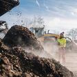 Woman worker standing with clipboard in industrial compost plant