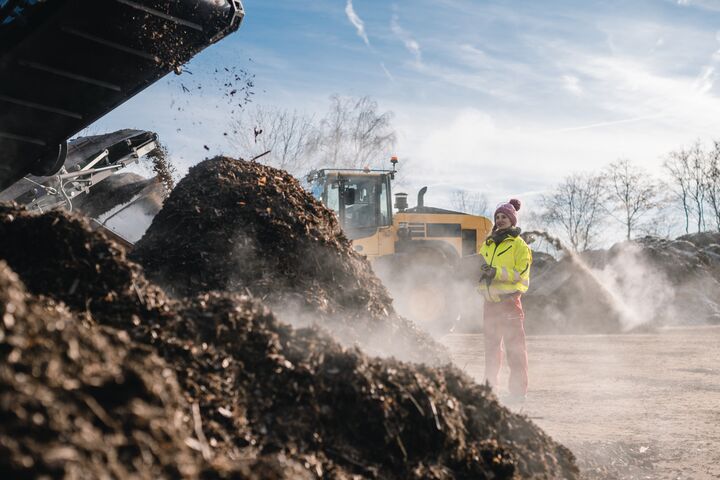 Woman worker standing with clipboard in industrial compost plant