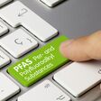 Per- and Polyfluoroalkyl Substances Written on Green Key of Metallic Keyboard. Finger pressing key.