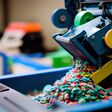 A close up of a recycling machine sorting plastic waste in a recycling factory, with a backdrop of conveyor belts.