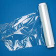 big roll of wound white transparent film for wrapping food, dark blue background, top view