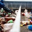 Worker in gloves sorts trash on conveyor belt in waste recycling plant workshop closeup. Plastic bottles reusing. Rubbish processing industry