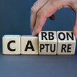 Carbon capture symbol. Businessman turns wooden cubes and changes the concept word Carbon to Capture. Beautiful grey table grey background. Business ecological carbon capture concept. Copy space.