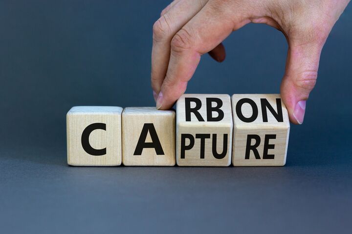 Carbon capture symbol. Businessman turns wooden cubes and changes the concept word Carbon to Capture. Beautiful grey table grey background. Business ecological carbon capture concept. Copy space.