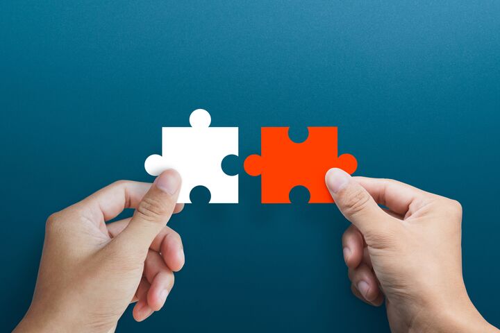 Businessman hands connecting puzzle pieces representing the merging of two companies or joint venture, partnership, Mergers and acquisition concept