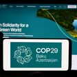 Stuttgart, Germany - 06-14-2024: Person holding cellphone with logo of United Nations Climate Change Conference 2024 COP29 in front of webpage. Focus on phone display.