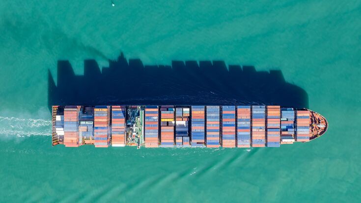 Aerial view of a cargo ship transporting shipping containers across the ocean. The vessel is moving goods for international trade and commerce. , AUCKLAND, NZ