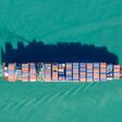 Aerial view of a cargo ship transporting shipping containers across the ocean. The vessel is moving goods for international trade and commerce. , AUCKLAND, NZ