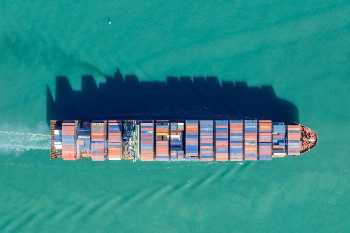 Aerial view of a cargo ship transporting shipping containers across the ocean. The vessel is moving goods for international trade and commerce. , AUCKLAND, NZ