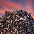 scrap metal heap at recycling junk yard against red sky at sunset