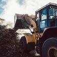 Earth mover working on pile of compost in industrial facility