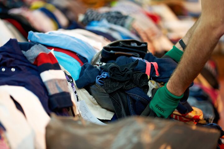 Person sorting second hand clothes by size and gender.