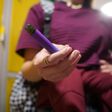 Teen girl holding a vape device in school hallway. Highschool problems.