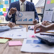 Group of confident business people point to graphs and charts to analyze market data, balance sheet, account, net profit to plan new sales strategies to increase production capacity.