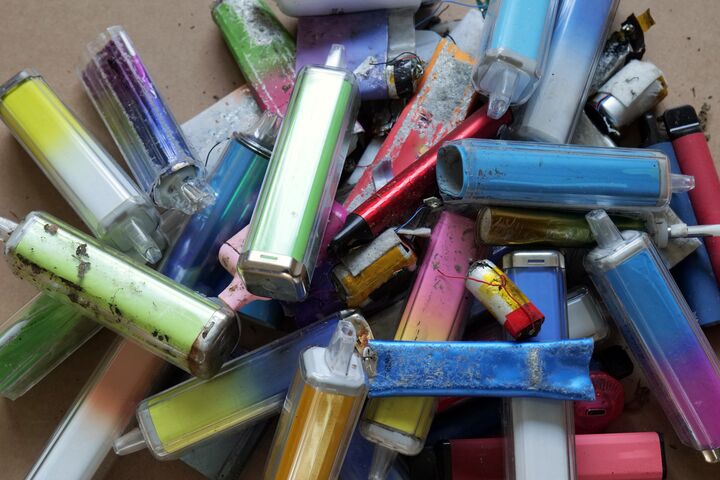 Discarded electronic cigarette vapes that have been collected from roads and pavements shot over a pale cardboard background